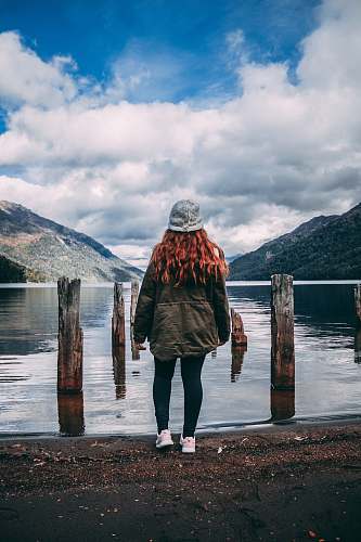 apparel woman standing facing body of water clothing