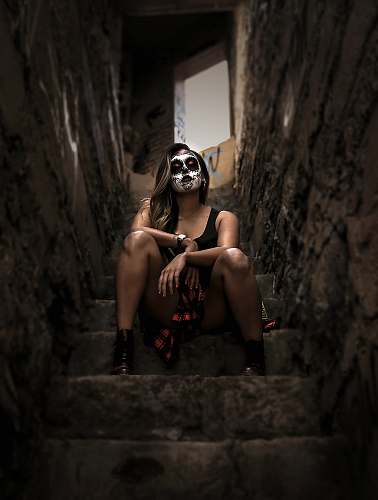 people woman wearing skull face paint sitting on stairs person