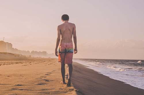 beach man walking beside sea shore sea