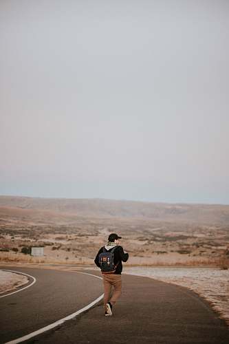 human man walking in middle of asphalt road people