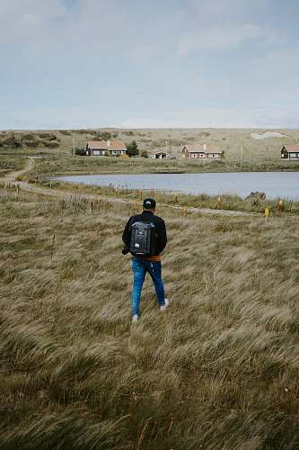 human person wearing blue denim skinny jeans and black jacket walking on the grass people