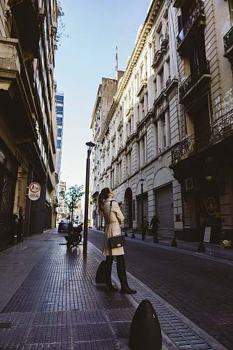 human woman standing on sidewalk beside post pedestrian