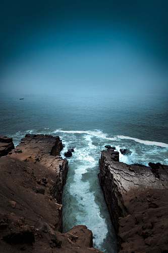 ocean aerial photography of cliff near body of water during daytime sea