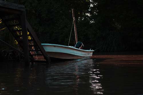 vehicle white boat docked in front of wooden stair during daytime vessel