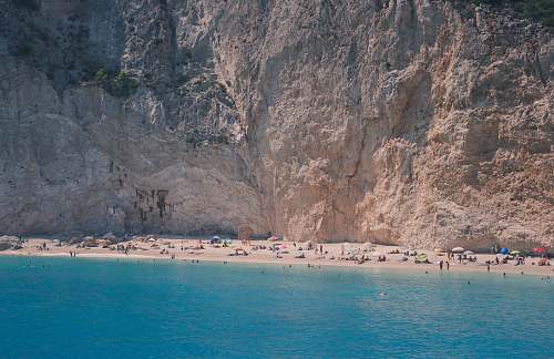 greece blue body of water near brown rock formation cliff