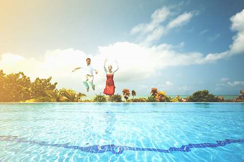 pool man and woman jumping onto pool sky