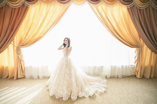 bride photo of woman wearing white gown near window curtain home decor