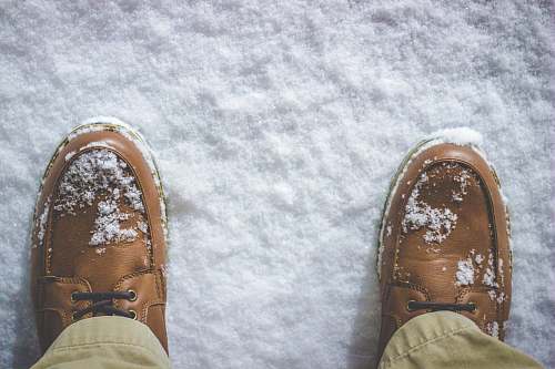 shoe top view photography of person standing on snow covered field feet
