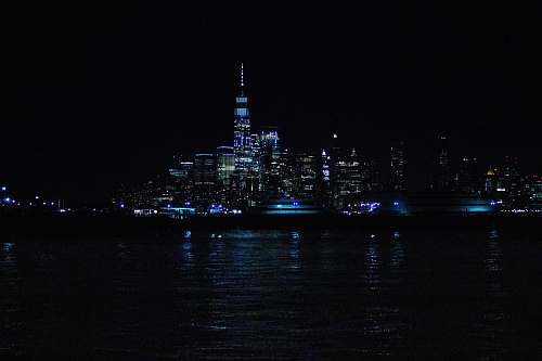 architecture aerial photography of city with high-rise buildings near body of water during night time tower