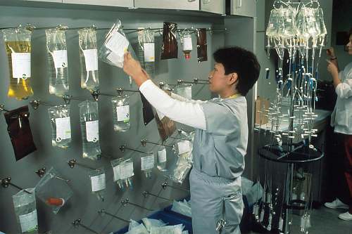 person man in white long sleeve shirt pouring water on clear glass bottles clinic