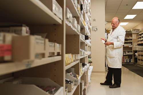 person woman in white dress shirt and black pants standing near brown wooden shelf shelf