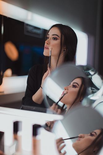 shallow focus photography of woman doing makeup