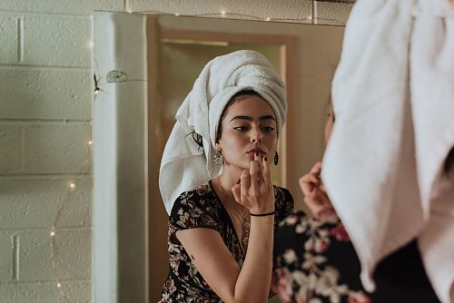 woman putting makeup in front of mirror