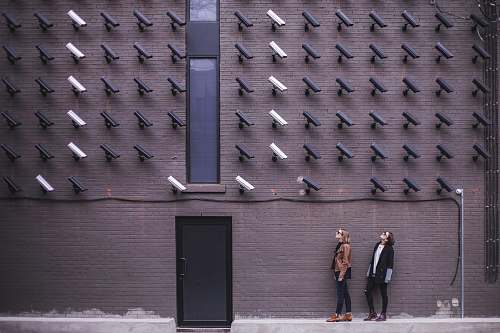  two women facing security camera above mounted on structure 