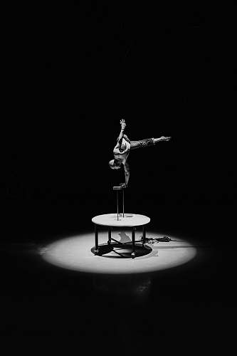 human grayscale photography of man doing stunts on round table person