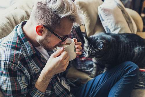 pet man drinking coffee during daytime cat