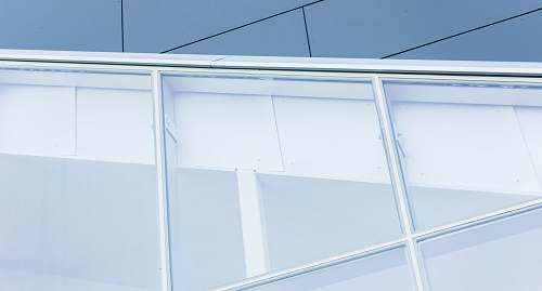 window A close view of a building with dark exterior and large, white-framed white windows cutting across at an angle architectural detail