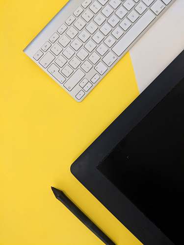 yellow gray Apple wireless keyboard beside black tablet computer and stylus pen keyboard