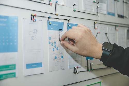 hand person working on blue and white paper on board ux