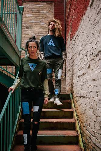 person A young woman and a young man walking down the stairs in an old brick stairwell human
