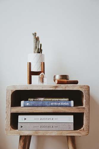 home books in brown wooden side table beside white wall design