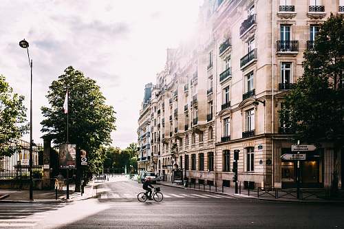 france man riding bike on middle of road near white concrete building building