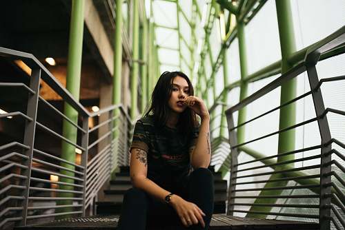 female woman in black crew-neck top sitting on stair woman