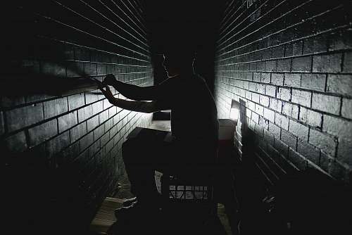 wall person sitting on dark room bricks