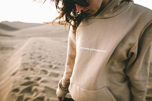 sand person wearing sunglasses and hoodie on sand desert