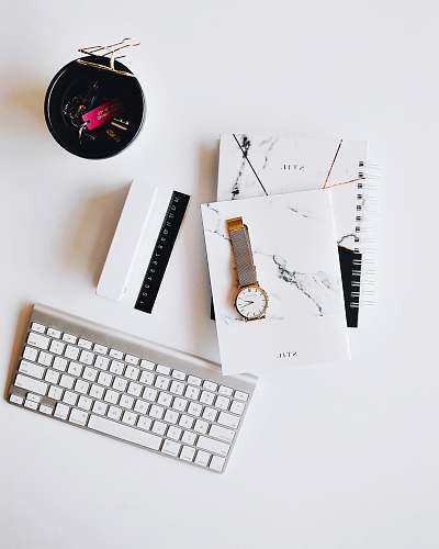 white Apple Magic Keyboard near round gold-colored analog watch with silver-colored mesh band with notebook on white surface photography keyboard