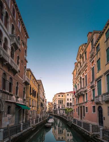 canal white boat on body of water between buildings water