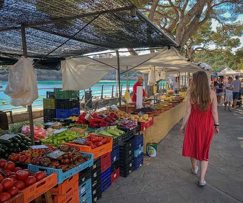  woman walking beside fruit and vegetable vendors 