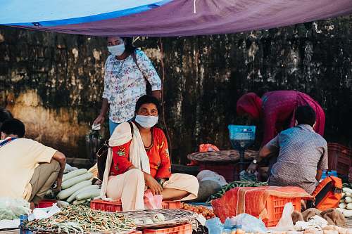 person woman in white and red dress sitting on brown woven basket market