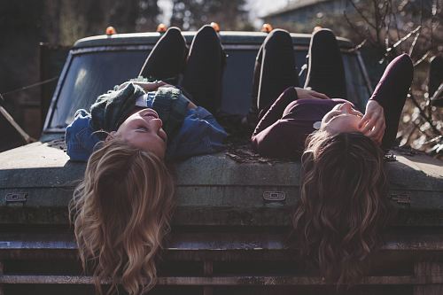 two women lying down on vehicle