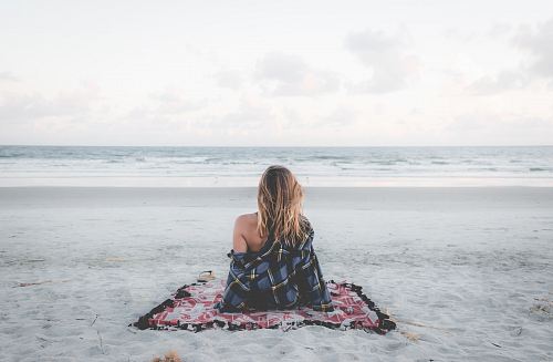 woman sitting on blanket located on shoreline
