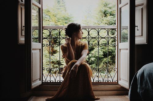 woman sitting on floor near window at daytime