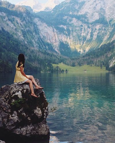 woman sitting on rock near lake