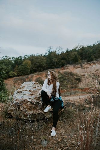 woman sitting on stone boulder outdoor