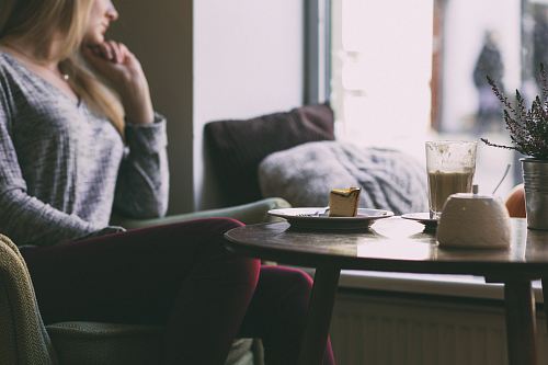 woman wearing gray long-sleeved shirt in front of table with piece of cake