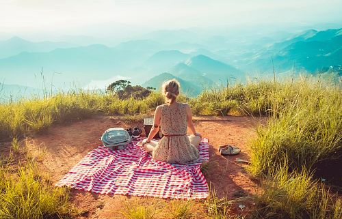 woman wearing gray sleeveless dress sitting on the picnic mat