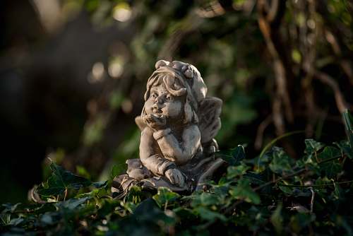 lion girl leaning forward figurine on green leaves mammal
