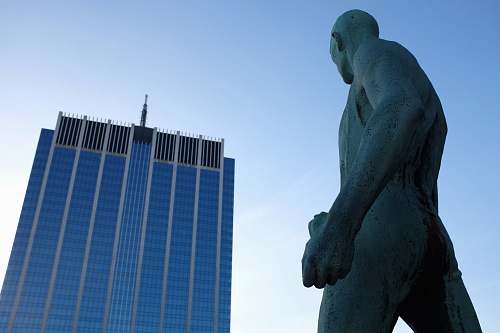 statue naked man statue in front high-rise building sculpture