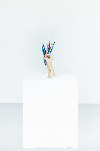 pencils person's hand burst out of box holding assorted-color pens hand