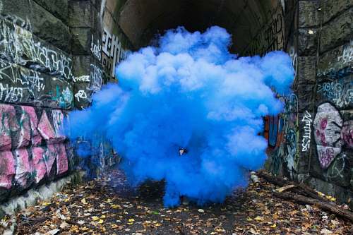 blue photo of blue smoke beside walls with graffiti smoke