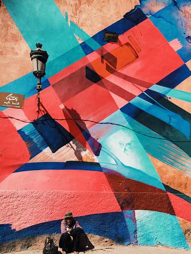 human man sitting on wall with artwork and lamp morocco