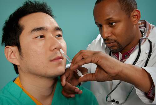 human doctor suctioning on man's nose patient