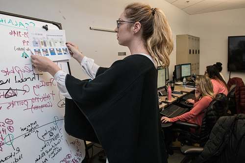 human woman in black blazer writing on white paper display
