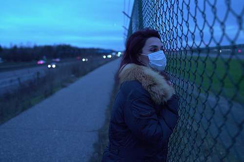 clothing woman in black jacket leaning on black metal fence during daytime apparel