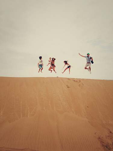 dune people jumping on sand sand