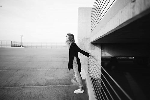 grayscale photography of woman standing near building